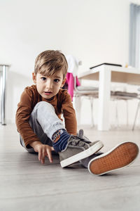 Portrait of cute boy sitting on floor at home