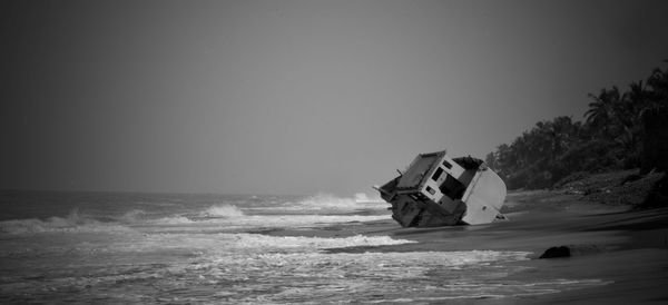 Abandoned ship in sea against clear sky