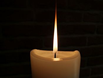 Close-up of lit candle in darkroom