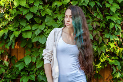 Portrait of young woman standing against plants