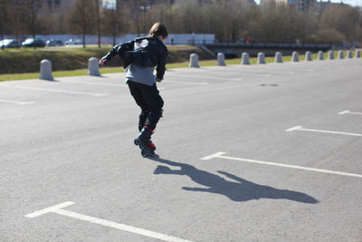 Rear view full length of man inline skating on road