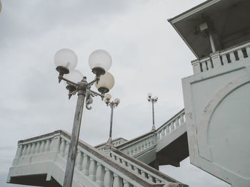 Low angle view of street light by building against sky