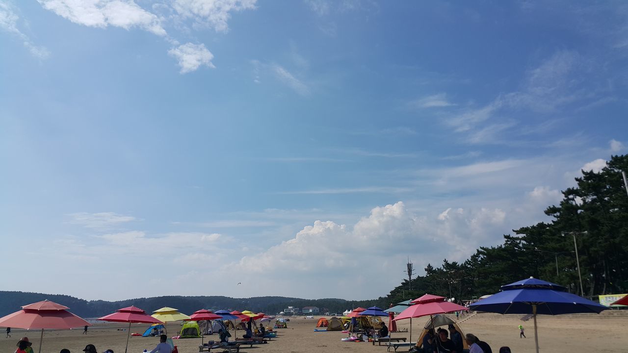 GROUP OF PEOPLE AT BEACH AGAINST SKY