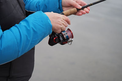 Midsection of man holding fishing rod