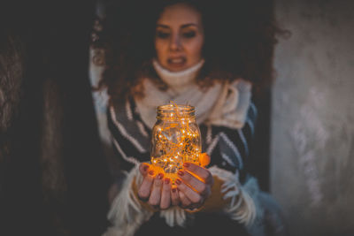Woman holding illuminated lights in jar