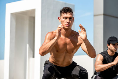 Young shirtless man exercising outdoors