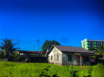Houses on grassy field against blue sky