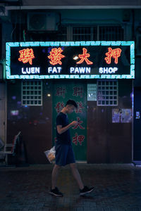 Full length of woman walking on illuminated street at night