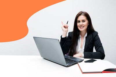 Portrait of a smiling young woman sitting on wall