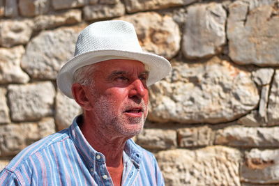 Portrait of man wearing hat against wall