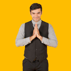 Portrait of young man standing against yellow background