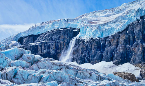 Glacier on rocky mountain against sky