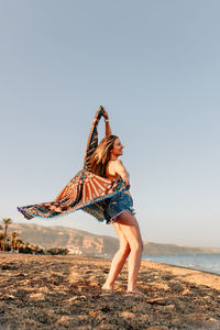 Woman standing on beach against clear sky