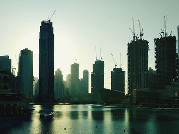 Modern buildings by river against sky in city