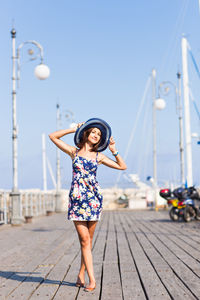 Full length of woman standing on pier against clear sky