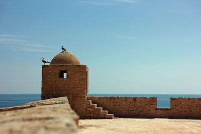 View of castle by sea against sky