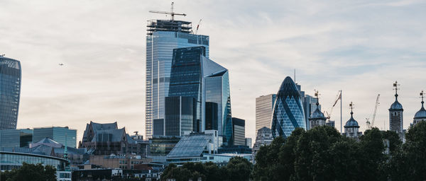 Skyscrapers in city against cloudy sky