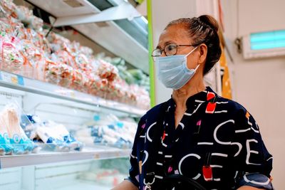 Woman looking way while wearing surgical mask in store