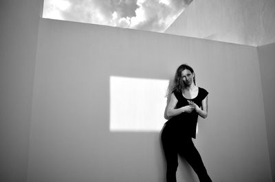 Full length of woman standing against wall