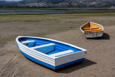 Boat moored on shore against blue sky