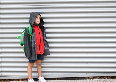 Portrait of young woman standing against corrugated iron