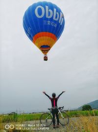 Rear view of man riding bicycle on field against sky