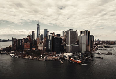 City at waterfront against cloudy sky