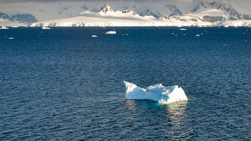 Scenic view of sea against snowcapped mountain