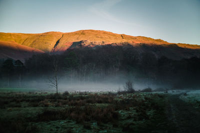 Misty valley with sunlit hills behind