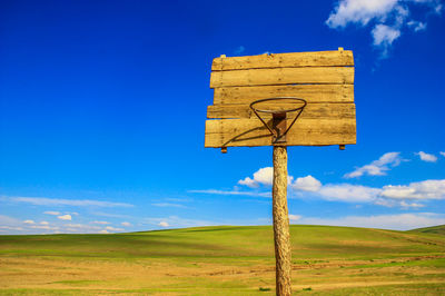 Information sign on field against blue sky