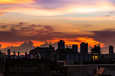 Buildings in city against romantic sky at sunset