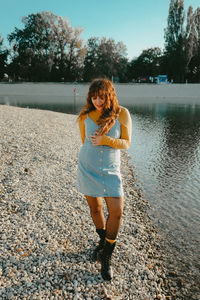 Full length portrait of young woman standing on pebbles