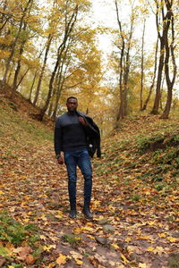 Full length of man standing amidst leaves in forest