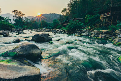 Stream flowing through rocks against sky