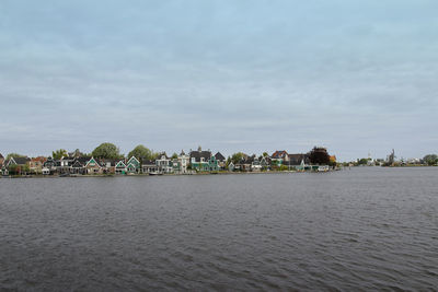 Scenic view of river by buildings against sky