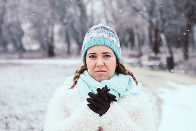 Portrait of young woman standing at park during winter