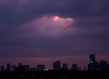 Silhouette buildings against dramatic sky during sunset