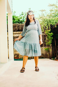 Full length of young woman standing against plants