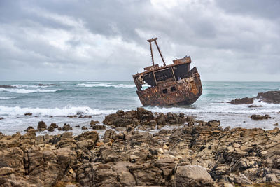 Abandoned ship on beach against sky