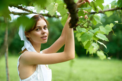 Portrait of young woman standing against plants