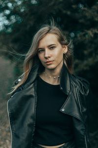 Portrait of young woman standing against waterfall