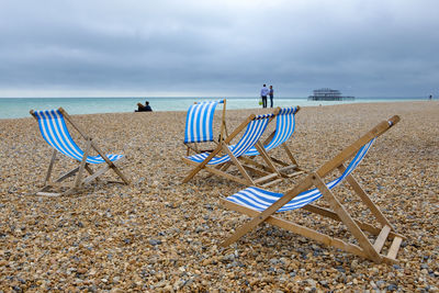 Chairs on beach against sky