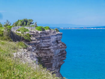 Rock formations by sea against blue sky