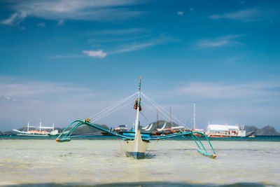 Sailboats moored in sea against blue sky