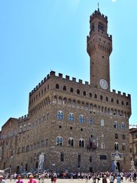 Group of people in front of historical building against clear blue sky