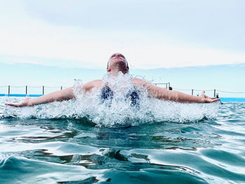 Man swimming in pool by sea against sky