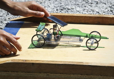 Cropped hand holding vehicle model with solar panel