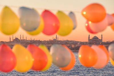 Close-up of multi colored balloons against sky during sunset