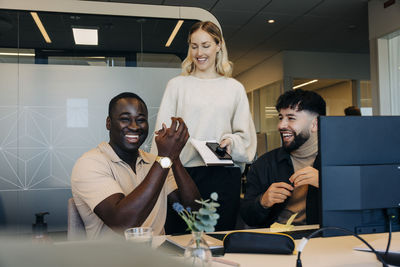 Happy businessman applauding with colleagues in coworking office