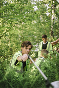 Teenage boy picking plastic garbage from green plant